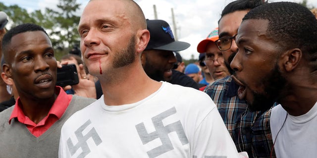 A man wearing a shirt with swastikas walks outside the location where white nationalist Richard Spencer gives a speech.