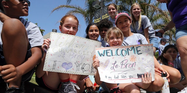 Children from Culver City Teen Camp are seen holding signs as they wait for the arrival of LeBron James at Blaze Pizza.