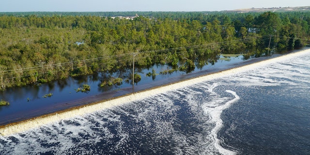 In this drone photo released by Duke Energy, flooding from the swollen Cape Fear River overtops an earthen dike at Sutton Lake, a 1,100-acre lake at the L.V. Sutton Power Station.