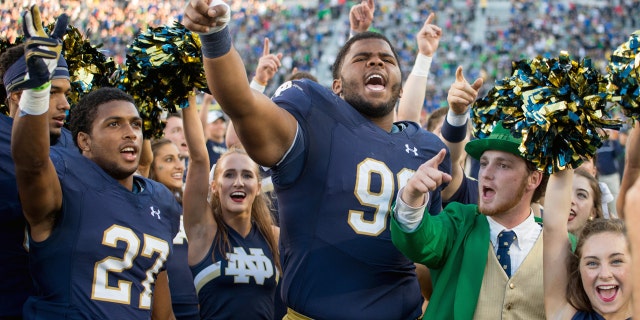 Notre Dame's leprechaun mascot celebrates with football players following a win in 2016.