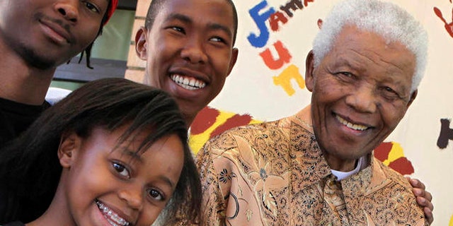 In this 2010 photo, Nelson Mandela, former South African president, right, is with his great-granddaughter Zenani Mandela, front left, Thembela Mandela, back left, and Mbuso Mandela, back right.