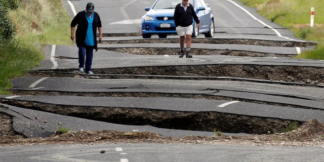 Local residents Chris and Viv Young look at damage caused by an earthquake, along State Highway One near the town of Ward, south of Blenheim on New Zealand's South Island, November 14, 2016. (REUTERS/Anthony Phelps)