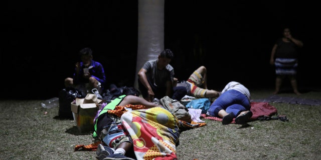 Central American migrants, who are participating in the annual Migrant Stations of the Cross caravan, go to sleep on the grass during the group's stop at a sports center in Matias Romero.