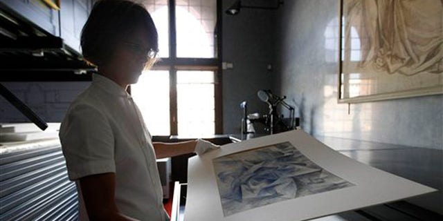 July 6, 2012: Francesca Rossi, curator in charge of the Sforzesco Castle drawings collection, looks at a work by Umberto Boccioni, in the same room where sketches by mannerist painter Simone Peterzano are preserved, in Milan.