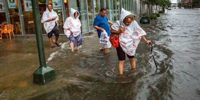 Philana Crite, of Cleveland who was in town for a family reunion, steps of the curb into flood waters in the New Orleans.