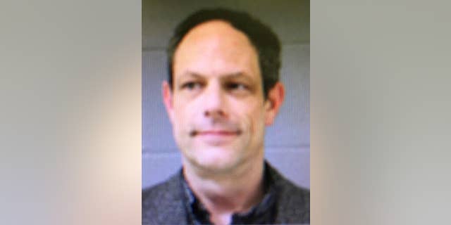 This booking photo released by the Newtown Police Department shows Jason Adams, arrested Wednesday, April 6, 2016, and charged with having a gun at the town's middle school. Adams, 46, a teacher at the school, was charged with possession of a weapon on school grounds, which is illegal in Connecticut. Police said he has a valid pistol permit. A gunman shot and killed 20 students and six educators at nearby Sandy Hook Elementary School in Newtown in December 2012. (Newtown Police Department via AP)