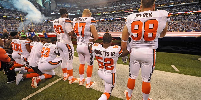 The Cleveland Browns team stand and kneel during the National Anthem before the start of their game against the Indianapolis Colts.