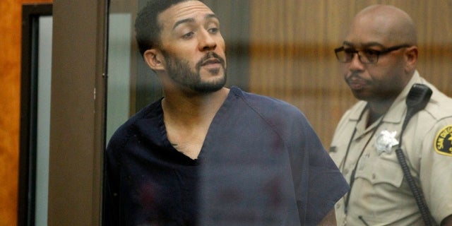 Former NFL football player Kellen Winslow Jr., center, looks through protective glass during his arraignment on Friday, June 15, 2018, in Vista, Calif.