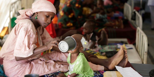 FILE- In this Monday, Aug. 29, 2016, file photo, a mother feeds her malnourished child at a feeding centre run by Doctors Without Borders in Maiduguri, Nigeria. Thousands of children already have died of starvation and disease in Boko Haram-ravaged northeastern Nigeria, Doctors Without Borders said Tuesday quoting a new survey that is forcing Nigerian officials out of a state of denial. (AP Photo/Sunday Alamba, File)