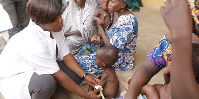 In this Sunday , May. 3, 2015 file photo a doctor attends to a Malnourished child as women and children rescued by Nigerian soldiers wait to receive treatment at a refugee camp in Yola, Nigeria.