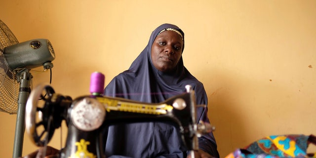 An unidentified internally displaced woman, who sews fabrics to sell, poses for a photograph in a community centre in Bama in northeast Nigeria, Nov. 23, 2017.