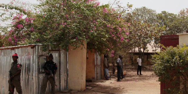 Security officers stand guard at the residence of abducted German archaeologists Johannes Behringer in Janjala Village, Nigeria.