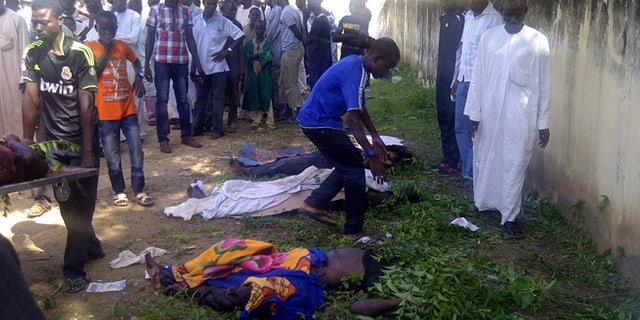 Sept. 29, 2013: In this image taken with a mobile phone, rescue workers and family members gather to identify the shrouded bodies of students killed following an attack by Islamist extremists on an agricultural college in Gujba, Nigeria.