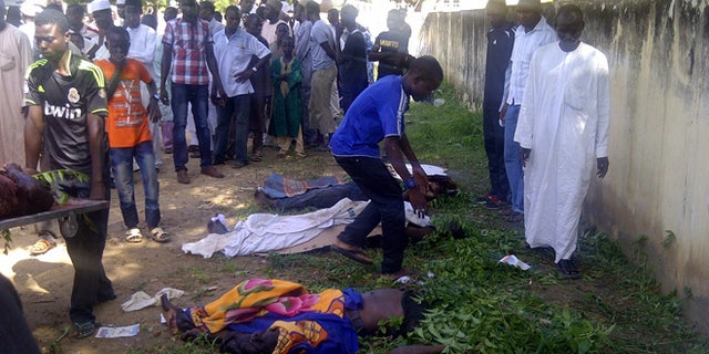 Sept. 29, 2013: In this image taken with a mobile phone, rescue workers and family members gather to identify the shrouded bodies of students killed following an attack by Islamist extremists on an agricultural college in Gujba, Nigeria.