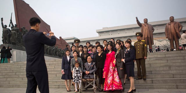 Apr. 15, 2014: A North Korean family poses for a souvenir photograph in front of bronze statues of the late leaders Kim Il Sung and Kim Jong Il at Munsu Hill in Pyongyang on the official birthday of Kim Il Sung.