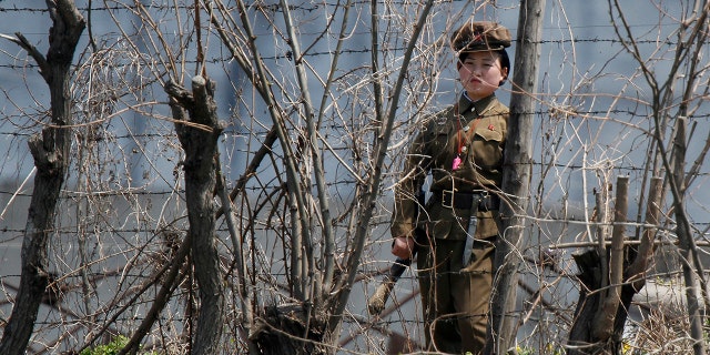 A North Korean prison policewoman stands guard behind fences at a jail on the banks of Yalu River near the Chongsong county of North Korea, opposite the Chinese border city of Dandong. Many Christians in North Korea are sent to prison camps where they are tortured for their faith.