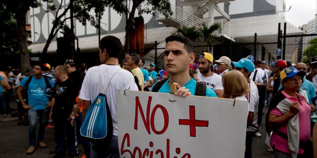 A young man holds poster that reads 'No more Socialism'  in Caracas, Venezuela, Thursday, Sept 1, 2016.