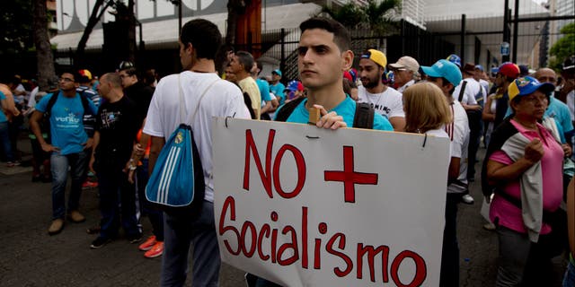 A young man holds poster that reads 'No more Socialism' in Caracas, Venezuela, Thursday, Sept 1, 2016.
