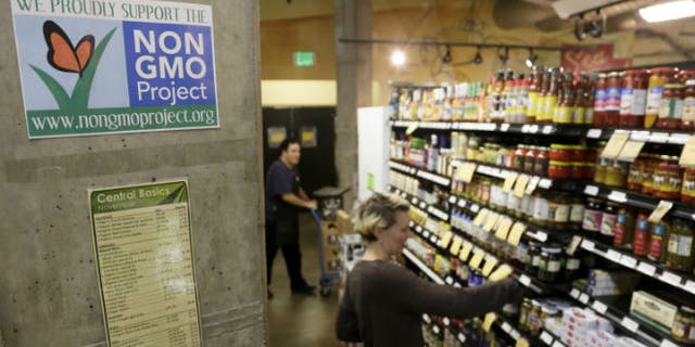 Employees stock shelves near a sign supporting non genetically modified organisms (GMO) at the Central Co-op in Seattle, Washington October 29, 2013. REUTERS/Jason Redmond