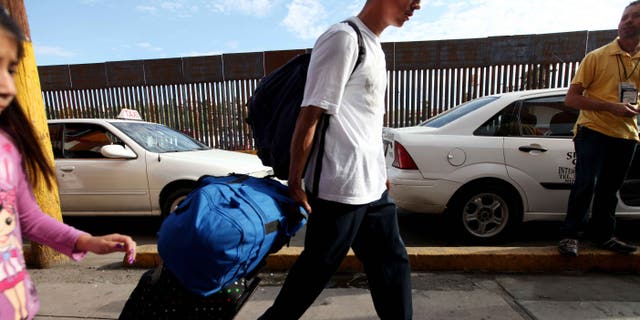 NOGALES, MEXICO - JULY 7: A mexican national carts his luggage towards the U.S-Mexico border on July 7, 2012 in Nogales, Mexico. The president-elect of Mexico, Enrique Peña Nieto, stated that he wants to expand his country's drug-war partnership with the United States but that he would not support the presence of armed American agents in Mexico. (Photo by Sandy Huffaker/Getty Images)