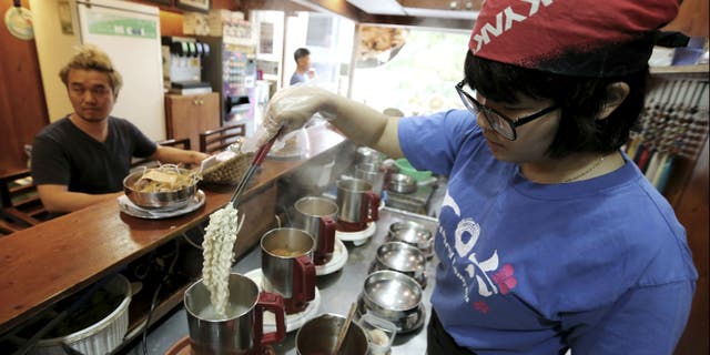 In this Aug. 19. 2014 photo, a cook prepares "ramyeon" instant noodles for Han Seung-youn, left, during an interview at a ramyeon restaurant in Seoul, South Korea. (AP Photo/Ahn Young-joon )