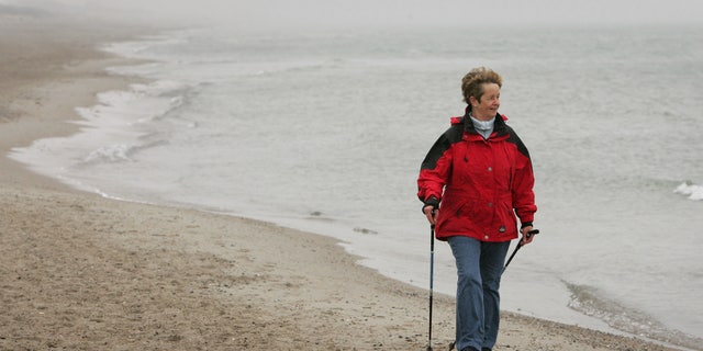 An elderly woman practices Nordic walking for rehabilitation exercise on the beach outside at a clinic in Damp on Germany's Baltic sea coast April 13, 2006. REUTERS/Christian Charisius - RTR1CQ1G