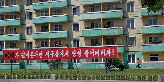 A woman walks outside an apartment building in Pyongyang where an anti-U.S. propaganda banner was put up in late June. But those who have visited the city in the wake of the Trump-Kim summit say some of that sentiment has started to disappear.