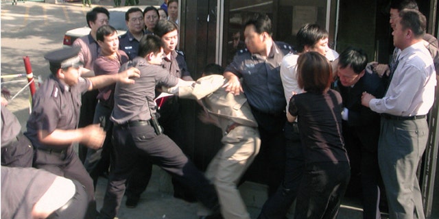 In this June 13, 2002 photo, Chinese security officers and officials at South Korean Embassy in Beijing scuffle in front of a police guard box next to the embassy's main gate as the security officers attempted to drag away a North Korean asylum seeker. Two North Koreans entered the embassy on June 13, 2002 amid a spate of asylum bids by North Koreans, but Chinese guards dragged an asylum-seeker from the visa office after punching and kicking diplomats who tried to block them.
