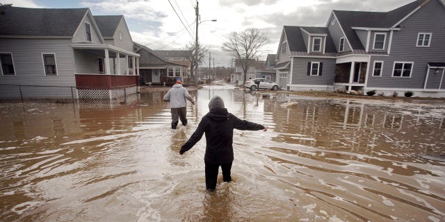 Kaylee Collin, right, and Spencer Stone walk through water along North Avenue in Camp Ellis in Saco, Maine on Sunday, March 4, 2018.