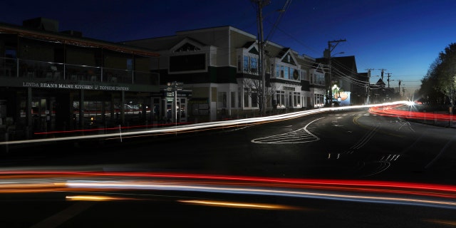 Lights from automobile traffic leave trails on a street in Freeport, Maine, where most outlet shopping stores are closed after a storm knocked out electricity.