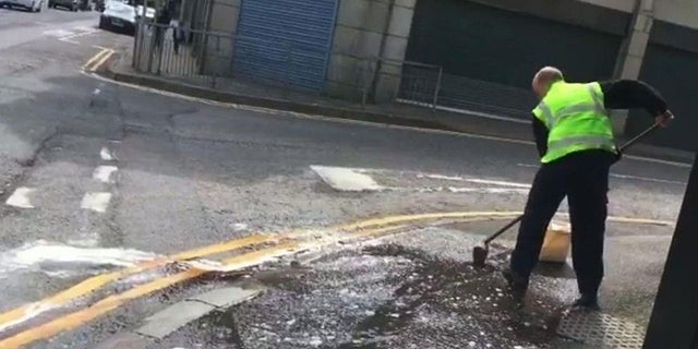 Workers clean the street after a woman was found covered in blood following an attack.