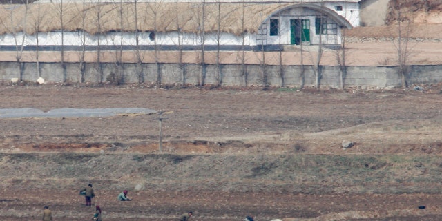 North Koreans work on a field in the propaganda village of Gijungdong near the truce village of Panmunjom in the demilitarized zone in Paju, 42 km (26 miles) northwest of Seoul, that separates North Korea from the South March 26, 2008. South Korea's new conservative government wants North Korea to answer questions about the fate of its prisoners of war and abducted civilians believed to be still held by the communist state, officials said on Tuesday. REUTERS/Lee Jae-Won (SOUTH KOREA) - RTR1YR7R