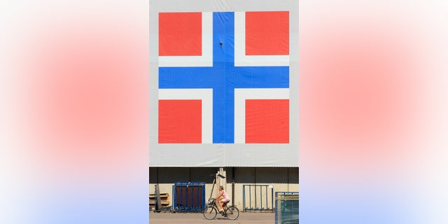 File photo - A woman cycles past a banner of the Norwegian flag attached to a warehouse in Oslo June 20, 2012. (REUTERS/Cathal McNaughton)
