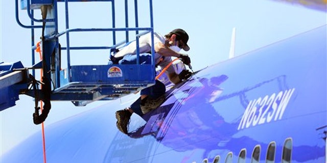 A member of the National Transportation Safety Board investigating the emergency landing of Southwest Airlines flight 812 cuts away a portion of the plane's fuselage on April 3 in Yuma, Ariz.