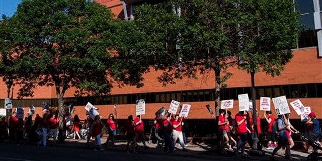Picketers walk in front of United Hospital in St. Paul, Minn., Sunday, June 19. 2016.