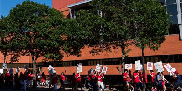 Picketers walk in front of United Hospital in St. Paul, Minn., Sunday, June 19. 2016.
