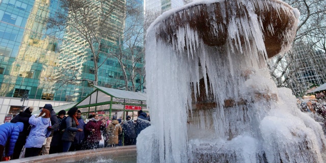 People pose for photos near a frozen water fountain in New York City's Bryant Park, Dec. 28, 2017.