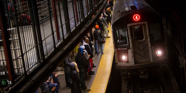 Commuters wait to ride New York City Subway in New York, December 12, 2013.
