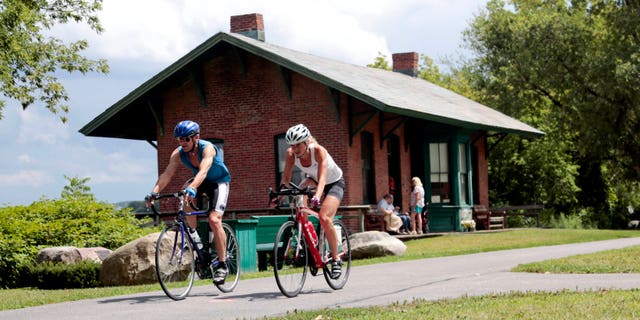 Cyclists pass the Niskayuna Train Station as they bike on the Canalway Trail in Niskayuna, N.Y. (AP Photo/Mike Groll, File)