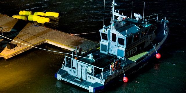 March 11, 2018: Yellow buoys that a New York police officer said are suspending a helicopter that crashed into the East River float next to a NYPD police boat at a pier in New York.