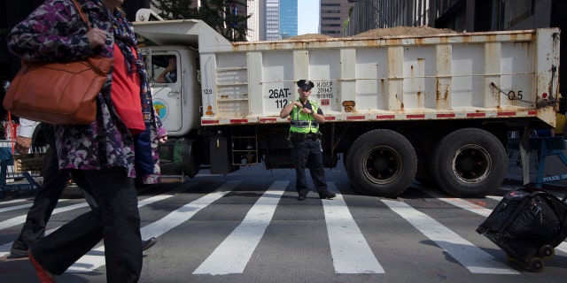 In this Sept. 24, 2015 file photo, a police office stands guard at a loaded dump truck that serves as a barricade along the perimeter of St. Patrick's Cathedral before the arrival of Pope Francis in New York.