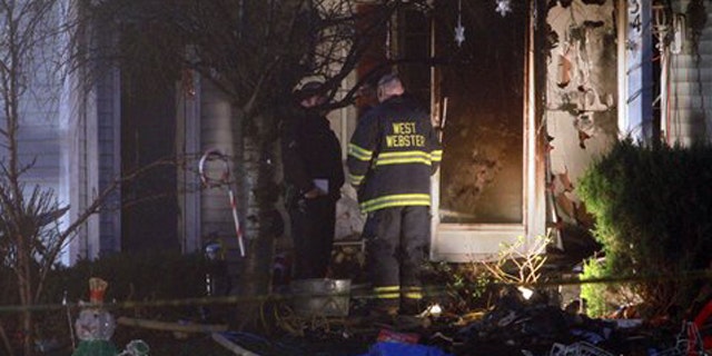 Emergency personnel investigate outside a home after a fire in Webster, NY on Wednesday, Dec. 7, 2011.