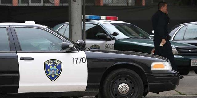 OAKLAND, CA - DECEMBER 06: An Oakland Police officer walks by patrol cars at the Oakland Police headquarters on December 6, 2012 in Oakland, California. Oakland City officials have come to an agreement to forfeit broad power over the Oakland Police Department to a court-appointed director to avoid federal takeover. The new compliance director would have the power to seek approval from a judge to fire the police chief. (Photo by Justin Sullivan/Getty Images)