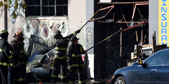 Firefighters clear an entry to a smoldering building after a fire tore through a warehouse party early Saturday, Dec. 3, 2016 in Oakland.