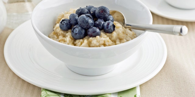 Large flake whole oatmeal with blueberries and brown sugar on white china makes a healthy breakfast