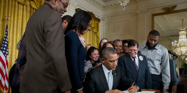 Feb. 12. 2014: President Obama, surrounded by workers, signs an executive order to raise the minimum wage for federal contract workers.