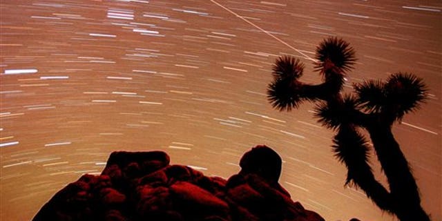FILE - In this Nov. 17, 1998, file time exposure photo, a meteor streaks through the sky over Joshua trees and rocks at Joshua Tree National Monument in Southern California's Mojave Desert. President Barack Obama is granting national monument status to nearly 1.8 million acres of scenic California desert wilderness, including land that would connect what is now Joshua Tree National Park to other established national monuments and national parks in the area. Obama, in California this week for a fund-raising swing, plan to make the announcement Friday, Feb. 12, 2016. (AP Photo/Reed Saxon, File)