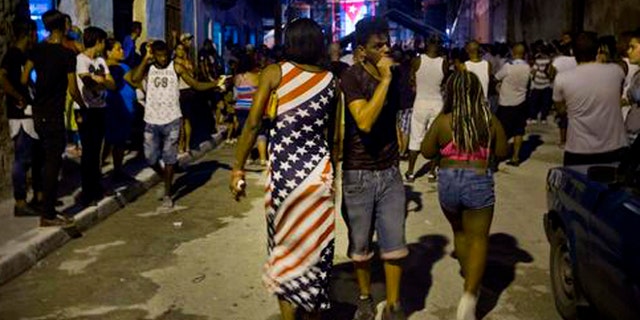 A woman wearing a dress with a U.S. flag motif walks to a concert by Silvio Rodriguez in Guanabacoa on the outskirts of Havana, Cuba, Friday, Sept. 9, 2016. President Barack Obama's easing of the U.S. trade embargo on Cuba has had virtually no positive effect on the island's economy, Cuba's top diplomat asserted Friday. (AP Photo/Ramon Espinosa)