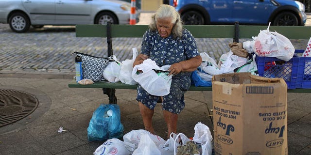 SAN JUAN, PUERTO RICO - JUNE 30: A woman sorts through her belongings on a park bench a day after the speech Puerto Rican Governor Alejandro Garcia Padilla gave regarding the government's $72 billion debt on June 30, 2015 in San Juan, Puerto Rico. The Governor said in his speech that the people will have to sacrifice and share in the responsibilities for pulling the island out of debt. (Photo by Joe Raedle/Getty Images)