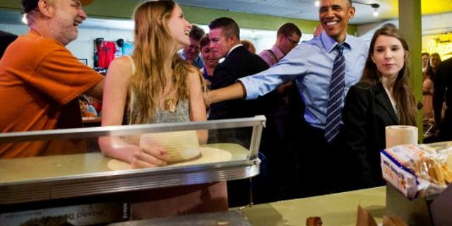 President Obama jokes with Bruce Finstad, left, and his daughter, Faith, as he orders food Thursday at Franklin Barbecue in Austin. (AP)